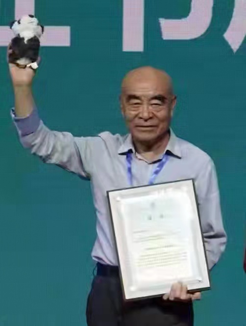 刘德天在颁奖台上左手持证书，右手高举玩偶熊猫